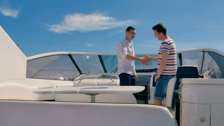 Two men shaking hands on a luxury yacht.