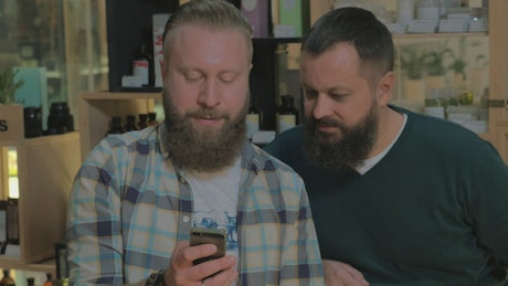 Two men with beards checking a phone
