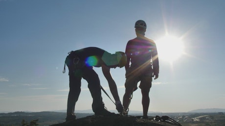 Two mountaineers on a peak under the blazing sun.