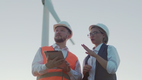 Two people inspecting wind turbines.