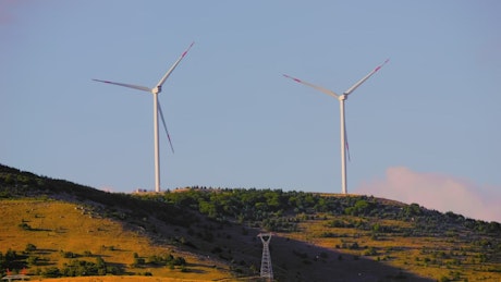 Two wind turbines spinning at sunset.