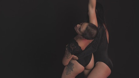 Two women dancing contemporary dance on a black background.