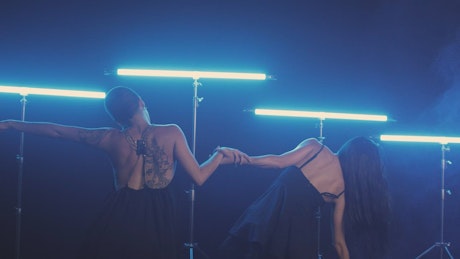 Two women dancing illuminated with blue light bars