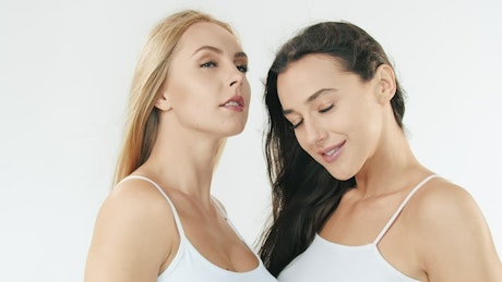 Two women with flawless skin on white background