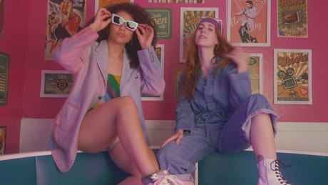 Two young girls having fun dancing and posing to the camera in a retro restaurant couch.