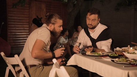 Two young men talking at a dinner party.