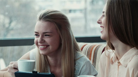 Two young woman laughing in the coffee shop.