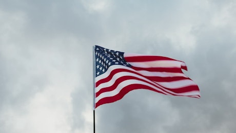 United State of America flag waving in cloudy sky.