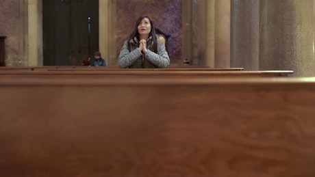 Upset woman praying in a church.