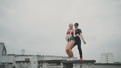 Urban couple dancing reggaeton on a rooftop.