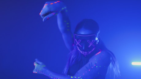 Urban girl dancing with a neon mask under a party light