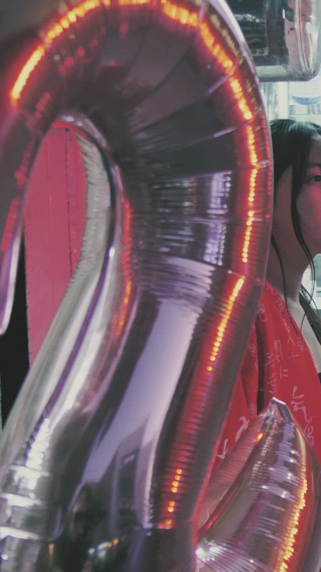 Urban girl holding birthday balloons.