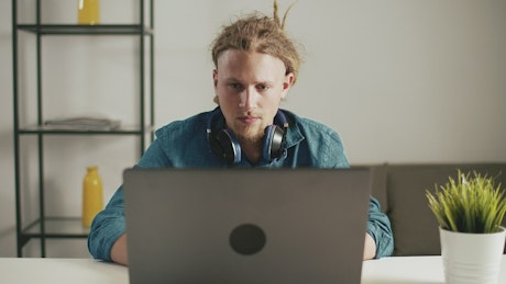 Urban man browses web on laptop with headphones.
