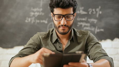Urban man smiling with tablet in classroom.