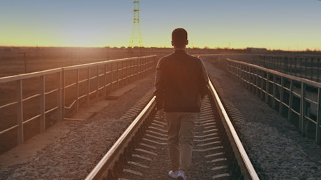 Urban man walking on the train tracks.