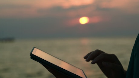 Using a tablet at sunset.
