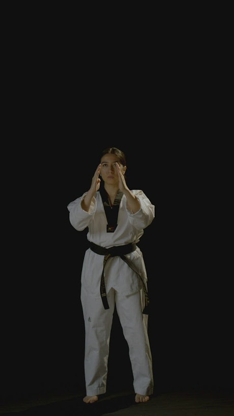 Vertical shot of a young karateka woman practicing karate.