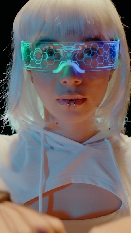 Vertical video with a young woman in futuristic attire wears a sci fi vision device to control the digital realm.
