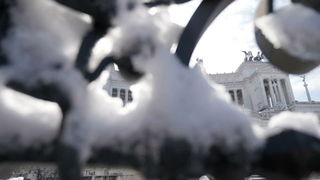 View of Vittoriano in Italy behind a snow-covered iron fence.