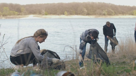 Volunteers cleaning up trash next to a river