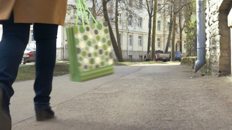 Walking with a green shopping bag.