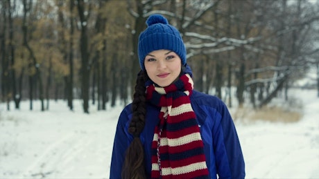 Warm woman during winter walking head-on in a forest.