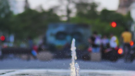 Water from a dancing fountain in a square.
