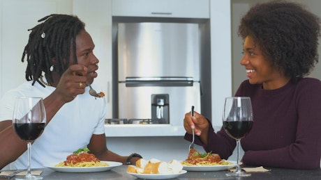 Wedding couple at a meal with spaghetti and wine in their apartment