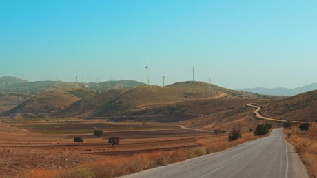 Wind turbines in the distance along a road.