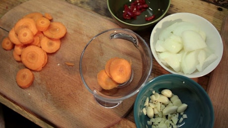 Woman adding chopped carrots to a bowl.