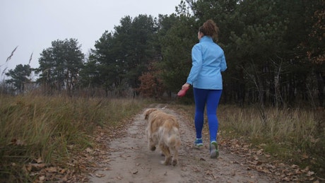 Woman and her dog running down a path