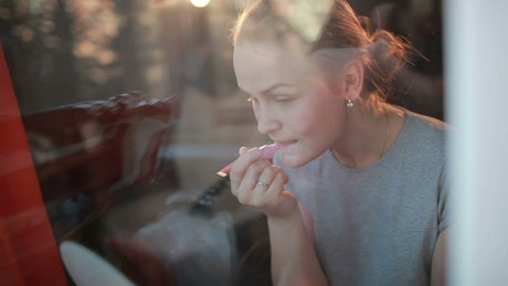 Woman applying pink lip gloss