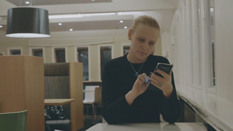 Woman browsing her phone in a hotel.