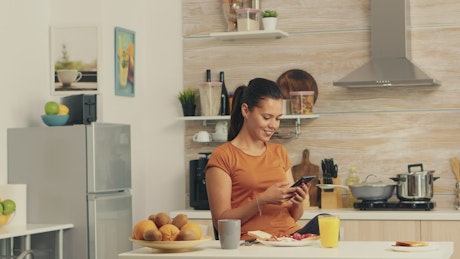 Woman checking cell phone during breakfast
