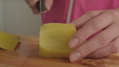 Woman cutting a kiwi into slices.