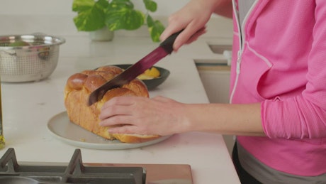 Woman cutting a slice of bread for breakfast.