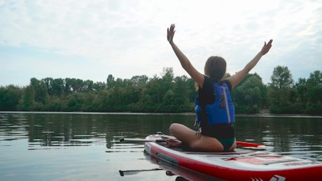 Woman does yoga routine on paddle board in river