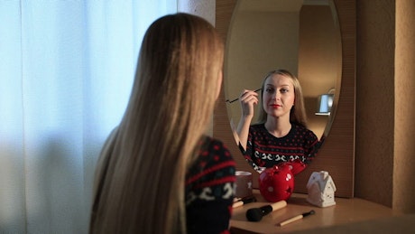Woman doing her makeup in the mirror.