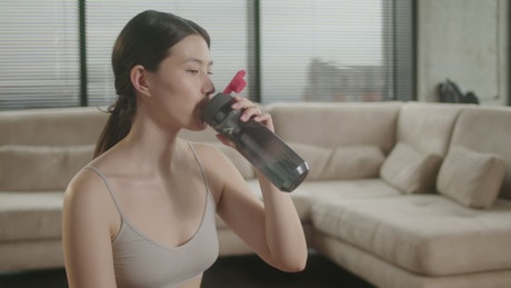 Woman drinking from her sports bottle after a workout.