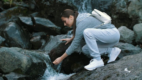 Woman drinks water from the waterfall.
