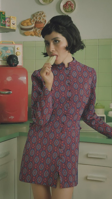 Woman eating a popsicle in the kitchen.