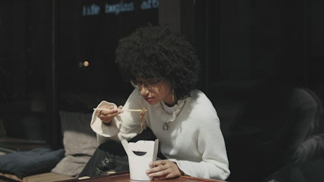 Woman enjoying a box of noodles.
