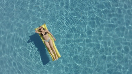 Woman enjoying summer sun at a pool.