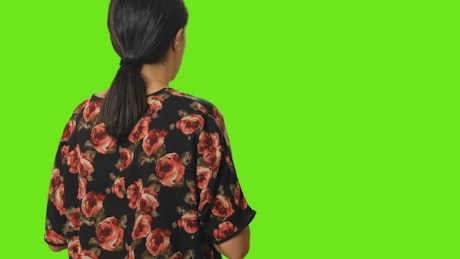 Woman from behind taking a photo on a green background.