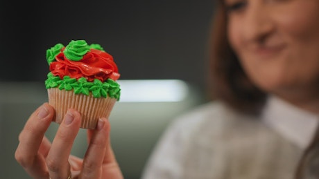 Woman holding a beautifully decorated Christmas cupcake.