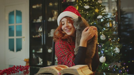 Woman holding her grey cat at Christmas.