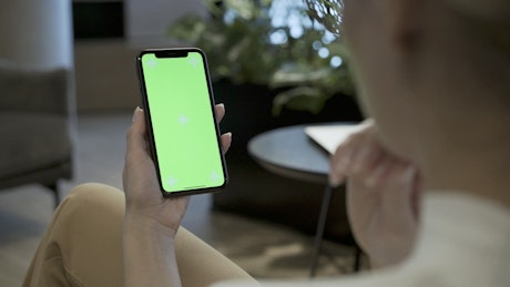 Woman holding mobile phone with a green screen.