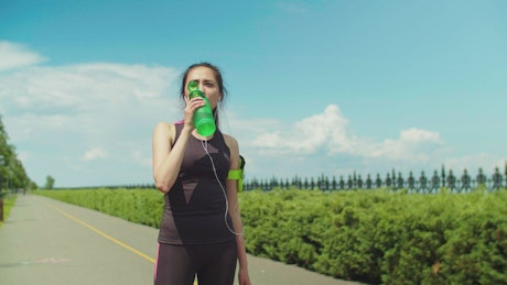 Woman in activewear drinking water after running.