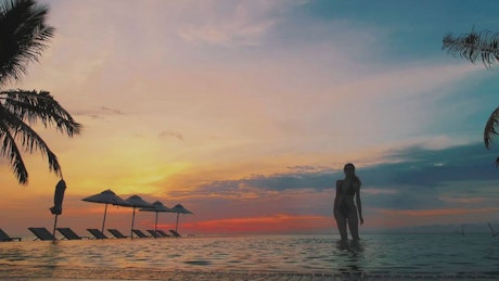Woman in an infinity pool at sunset
