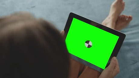 Woman in bare feet holds greenscreen tablet